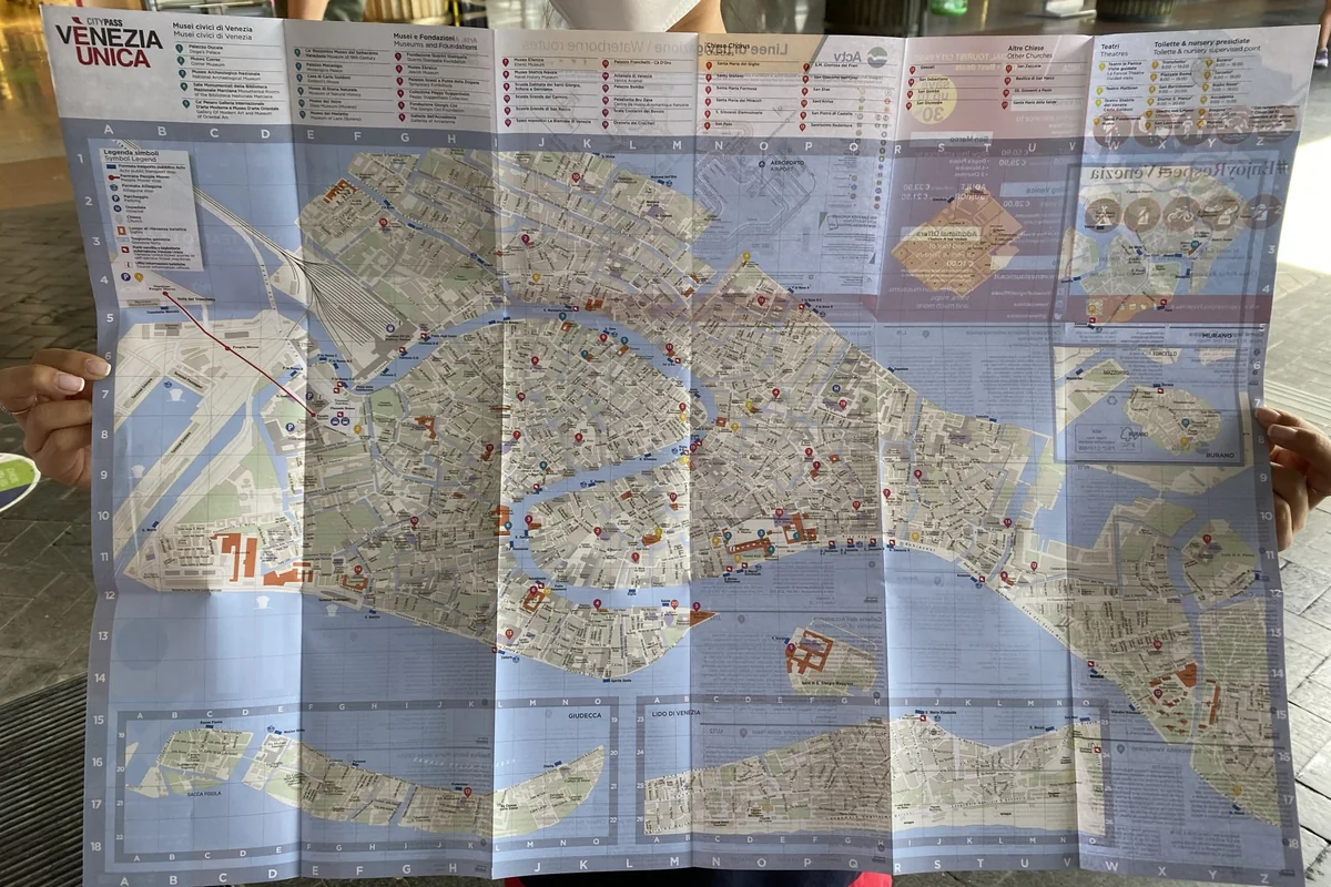Hands holding an open paper travel map while planning a multi-city route